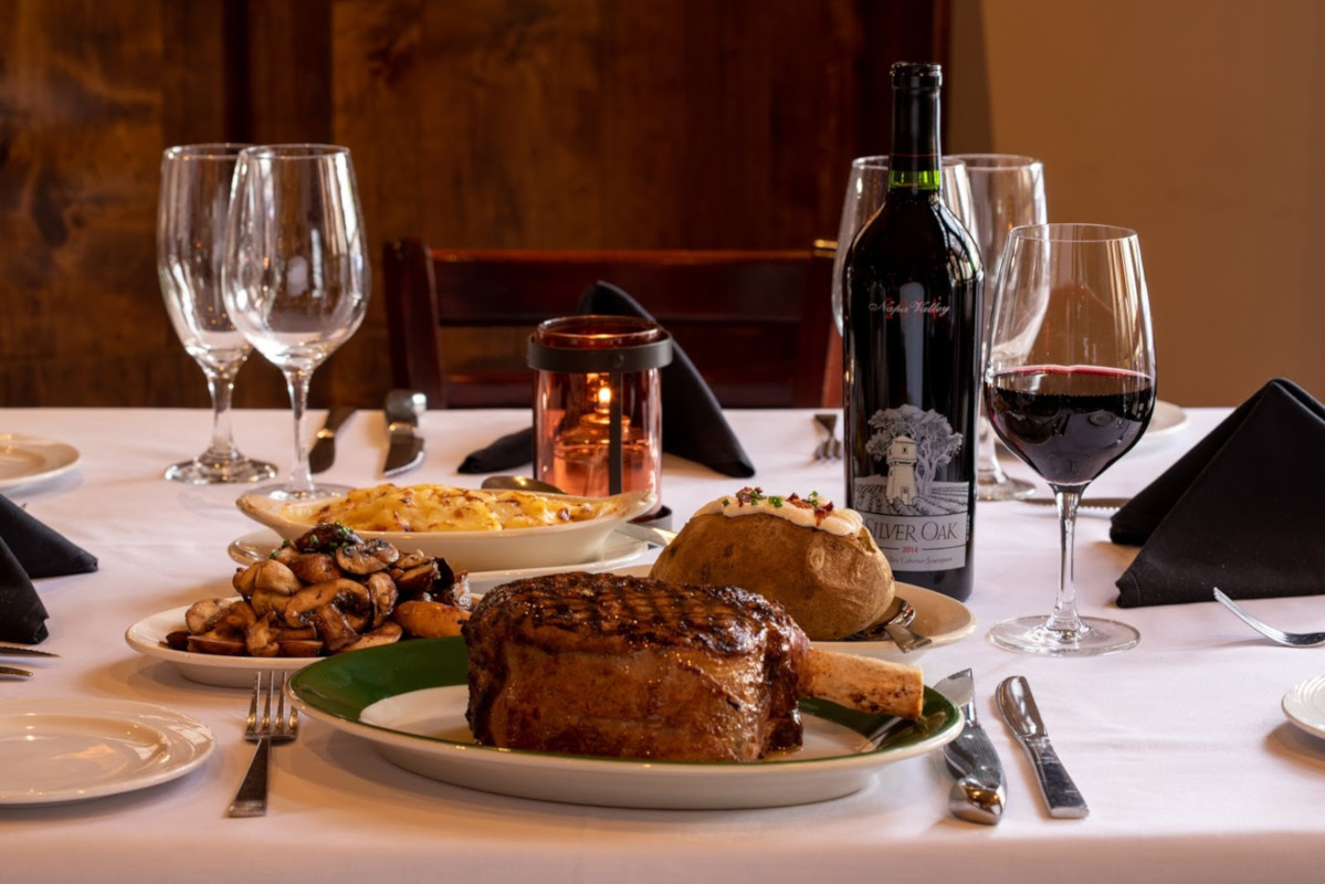 Different types of food on the table, bottle and glass of red wine